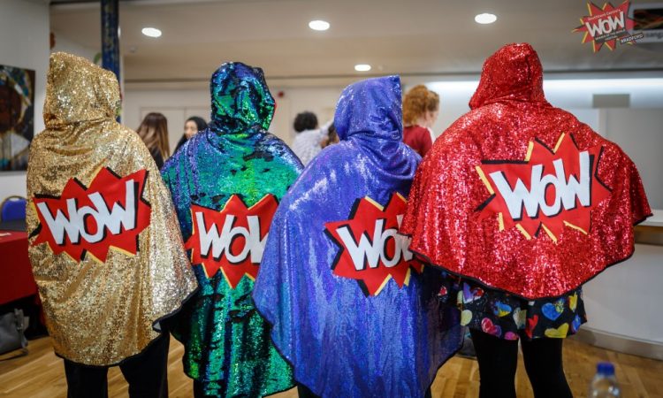 Four sparkly WoW capes being modelled here by four volunteers.